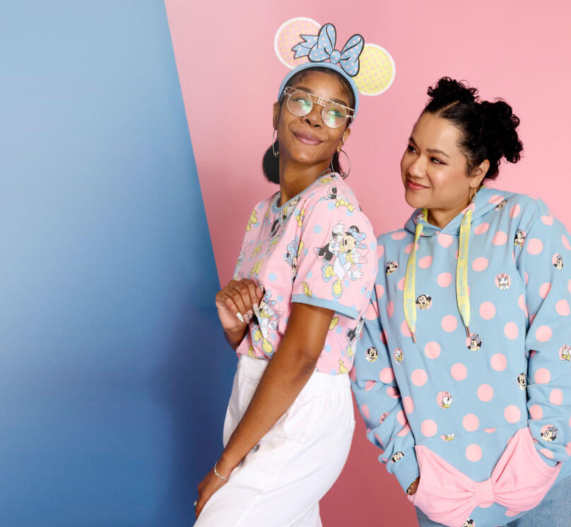 Pink and blue colored background with woman models wearing Loungefly Minnie Mouse Pastel Color Block Dots collection