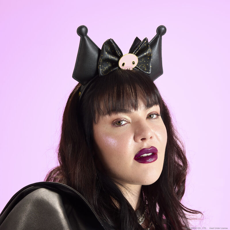 Woman with dark hair and bangs wearing the Loungefly Kuromi 20th anniversary ear headband. She stands against a light pink-purple background. 
